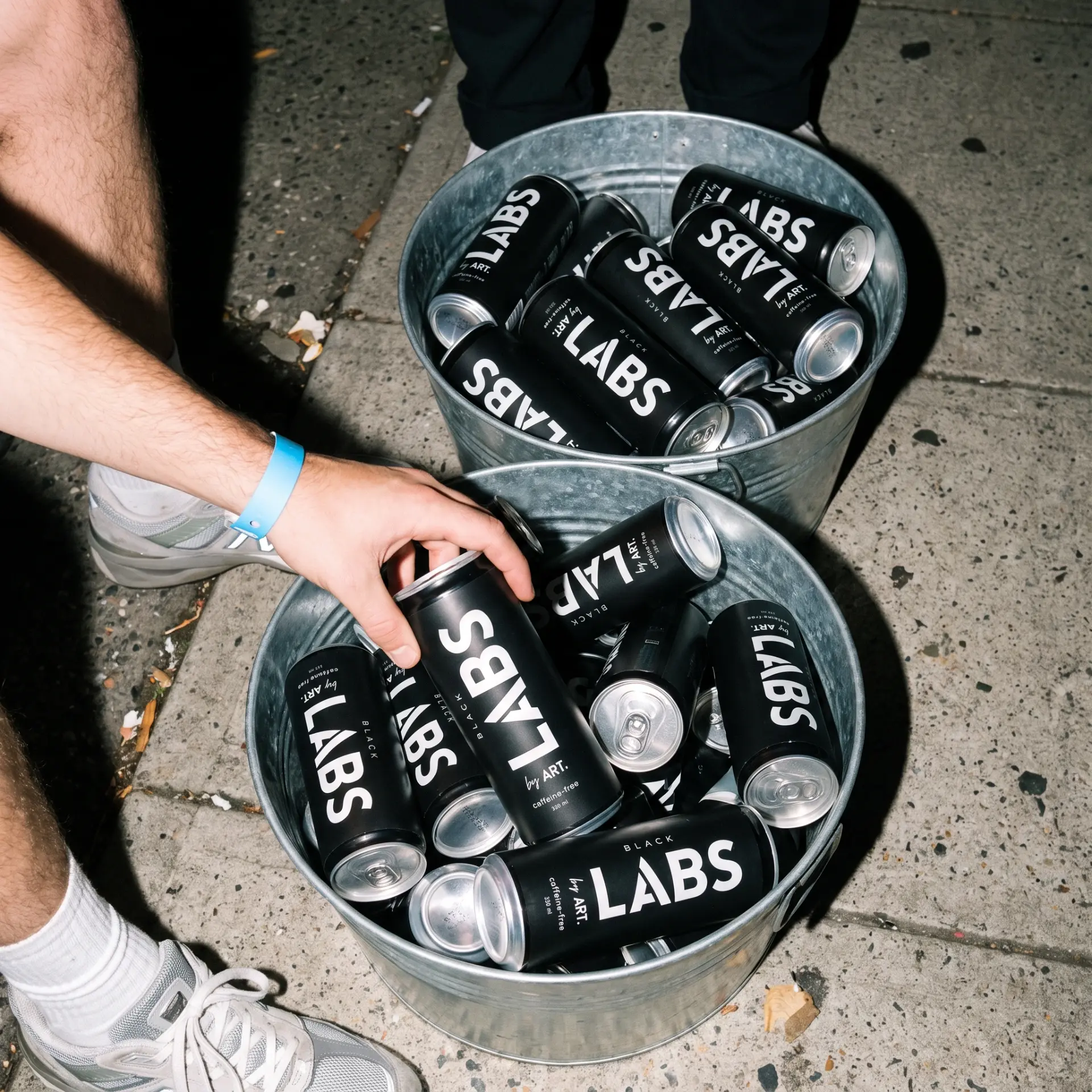 Buckets filled with matte black LABS cans on the street at night